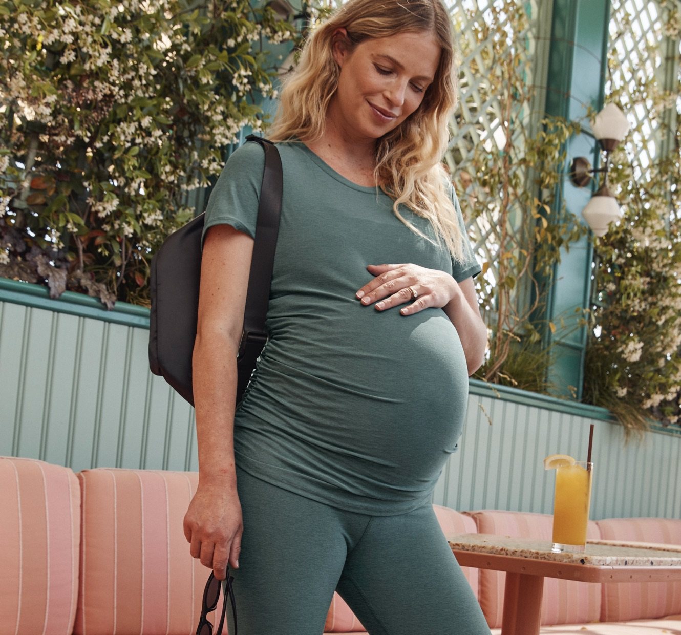 model is wearing a green maternity short sleeve t-shirt and green maternity midi leggings. 